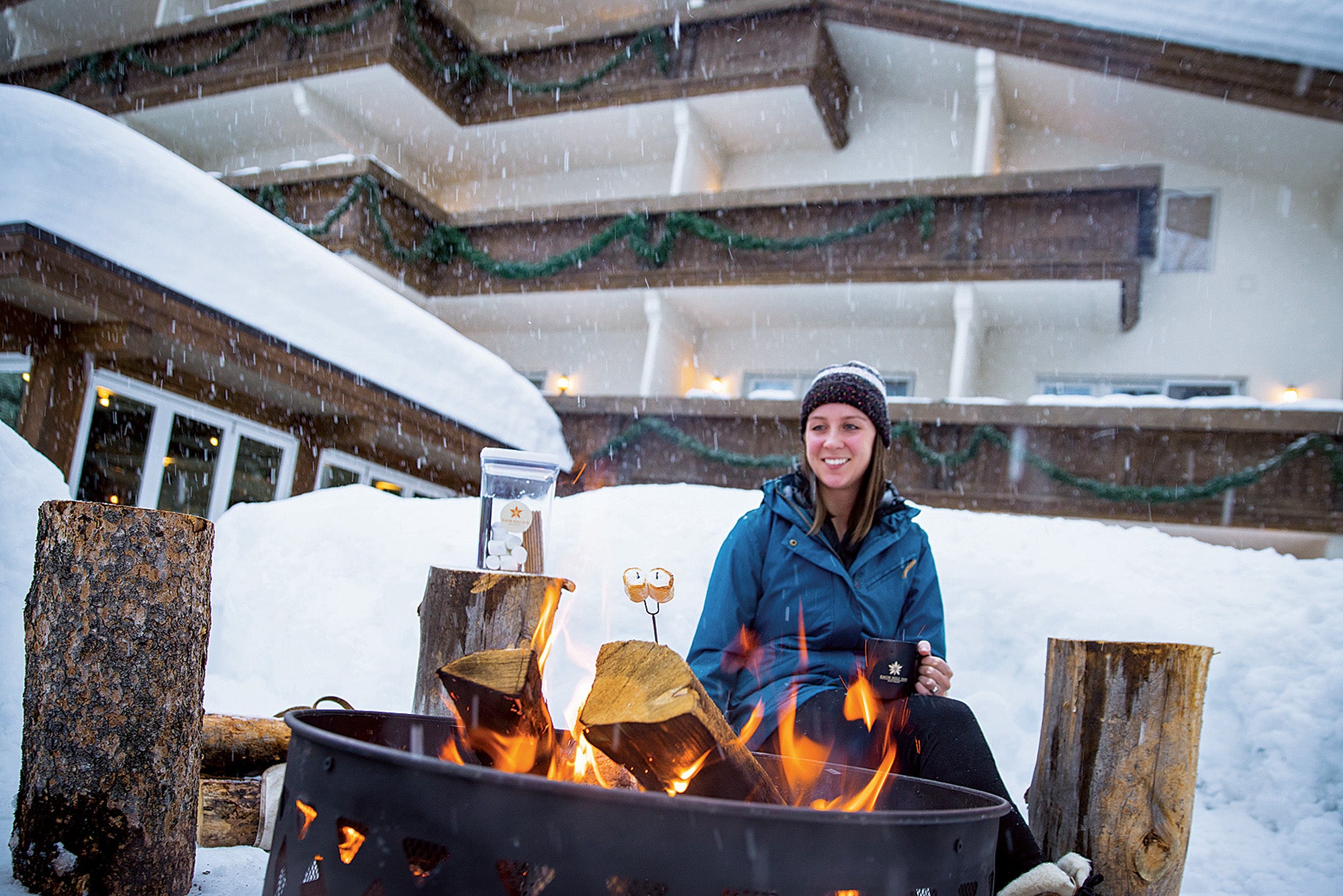 SKI1219-EC-Lodging-KnobHill Women in sitting in front of an outdoor fire pit in the snow at Knob Hill Inn