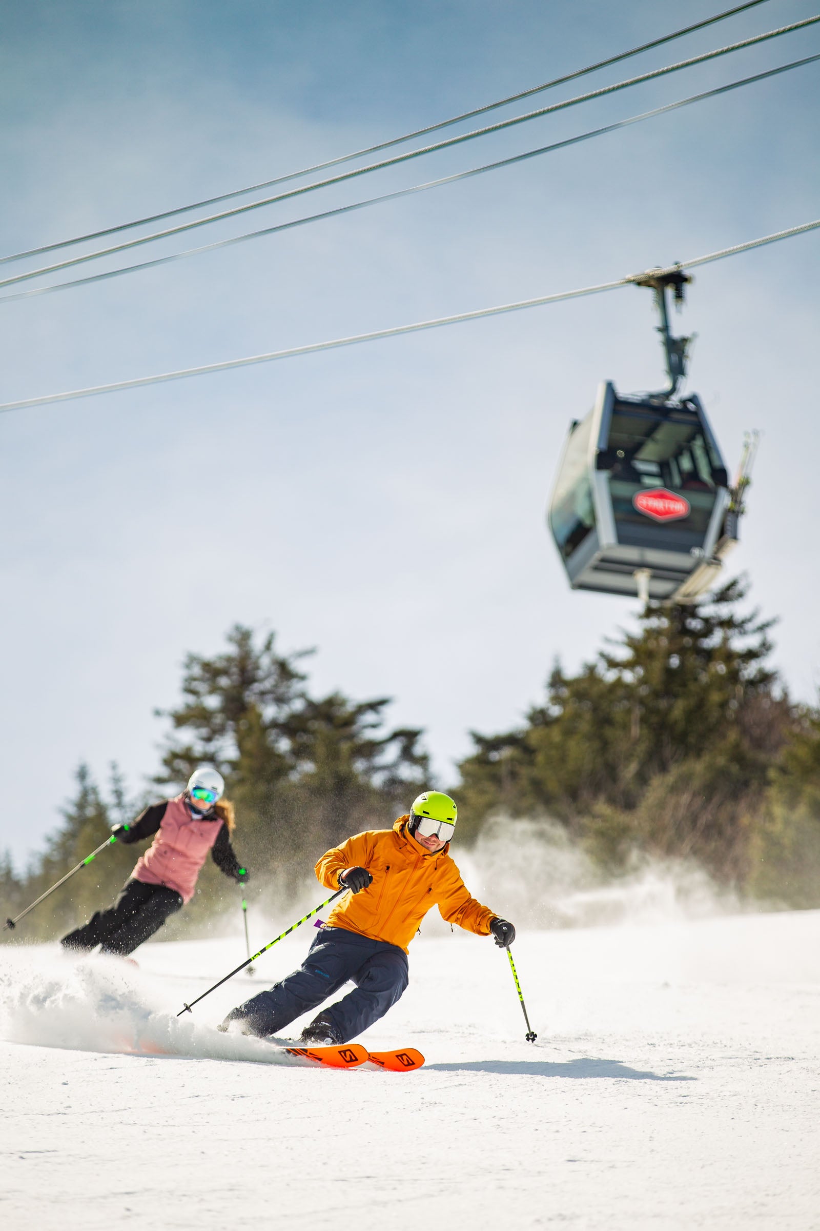 WEB JCash_Stratton_T4F6754 copy Two skiers skiing down a ski slope in front of the gondola at Stratton, Vermont