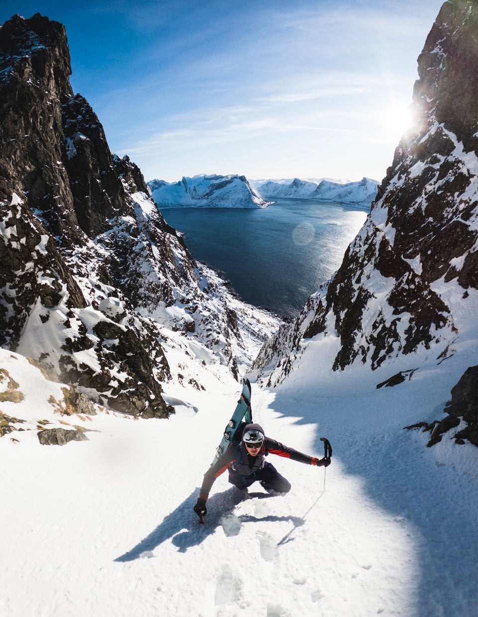 NDG_byNikolaiSchirmer-3977 (1) Skier boot-packing up a couloir in Norway with the sea in the background