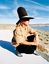 Glen Plank in a tall hat, overlooking a lake
