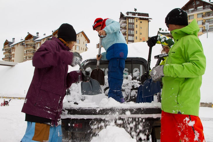 Team DubSatch unloads snow from the bed of a pickup truck to help build a kicker None