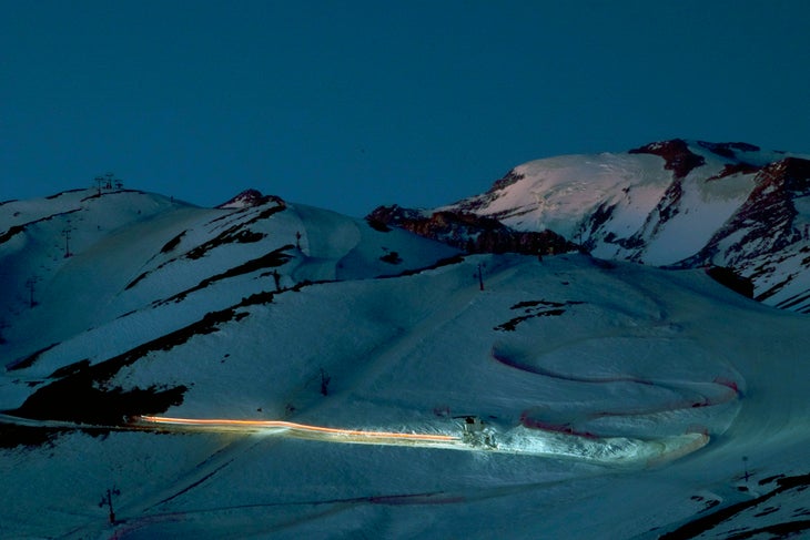 Groomers Get it Done Nighttime grooming operations leave streaks of light across the slopes at Valle Nevado as the last of the sun catches the glaciated peak of El Plomo.