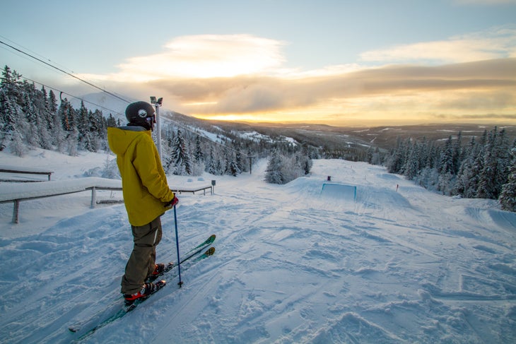 Surveying Andreas Sjöbeck looks over the terrain park of Vemdalsskalet during sunset in Northern Sweden.