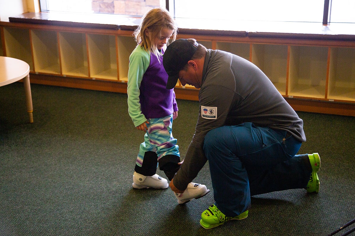 "Father helping daughter put on ski boots"