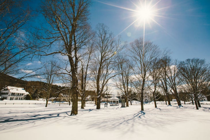 WEB Untitled 2 copy 2 Snow covered forested area with white houses and buildings in the back in Stratton, Vermont