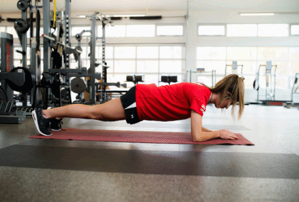 Athlete performs plank with arm extension move in gym