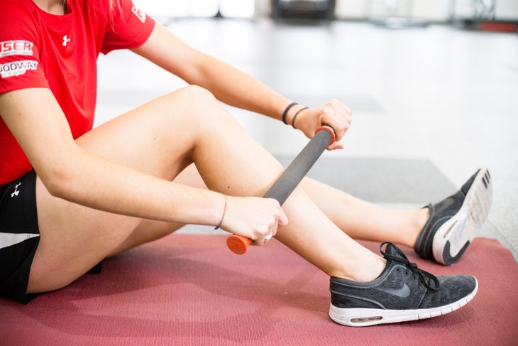Athlete using massage stick on shin muscles