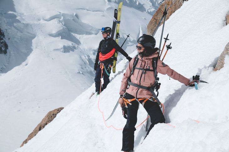 Two skiers roped together climbing with ice axes
