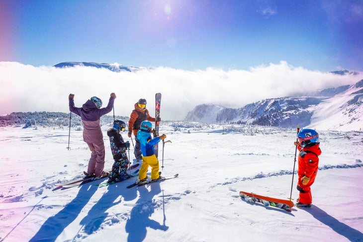 Family skiing and celebrating on the top of a mountain.