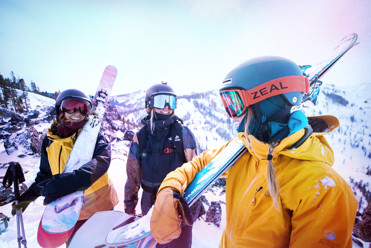 three people holding skis and laughing
