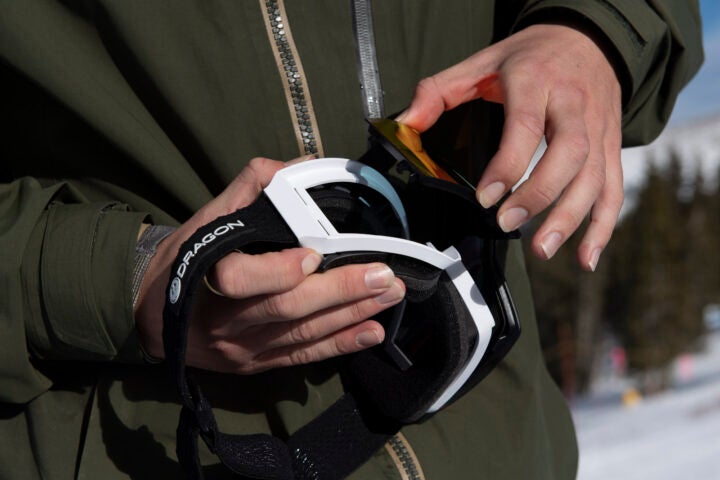 Someone changing the lens on their Dragon Alliance goggles
