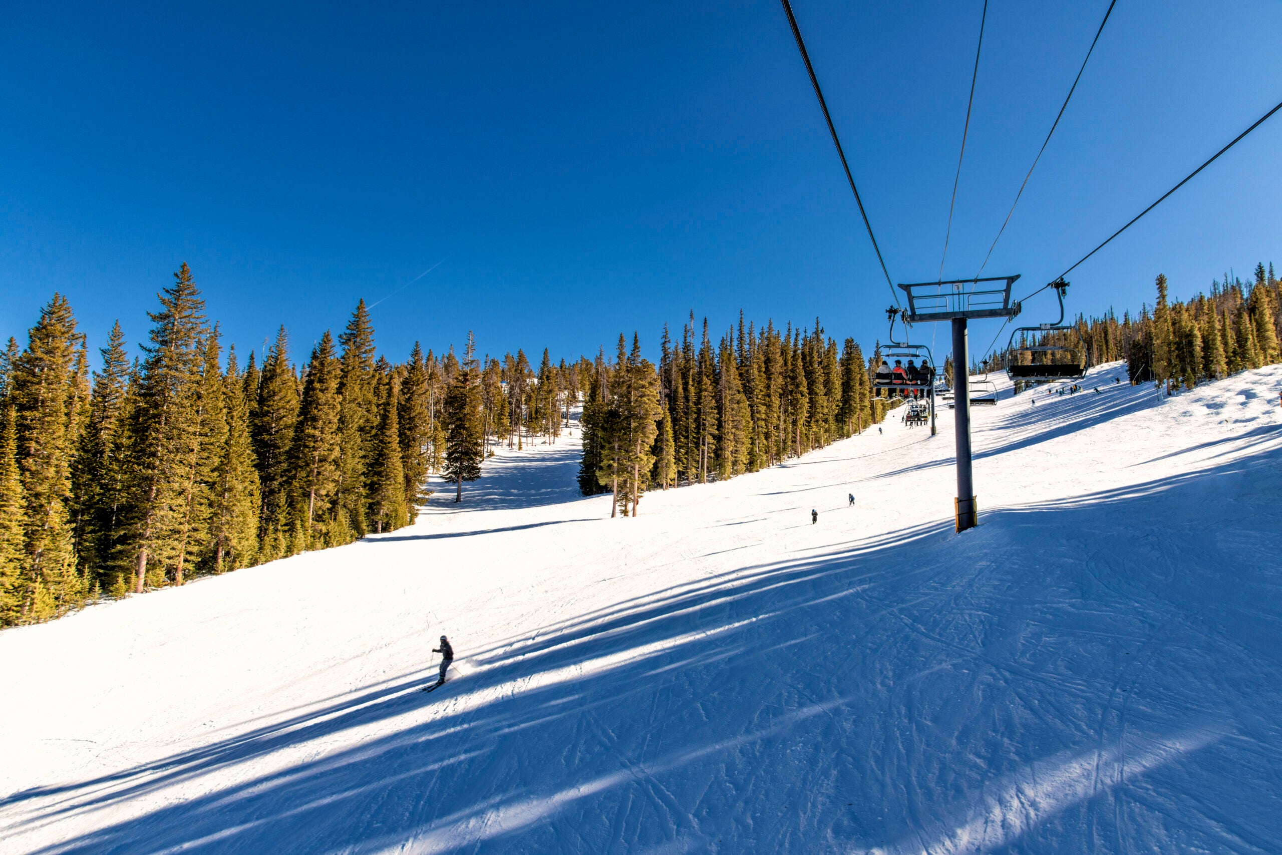 A ski lift up the side of a mountain at Winter Park, Colorado on a clear, mild winter afternoon.
