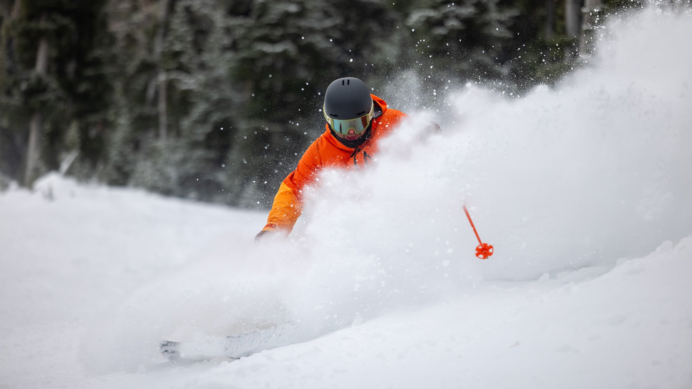 Skier in orange jacket skiing powder