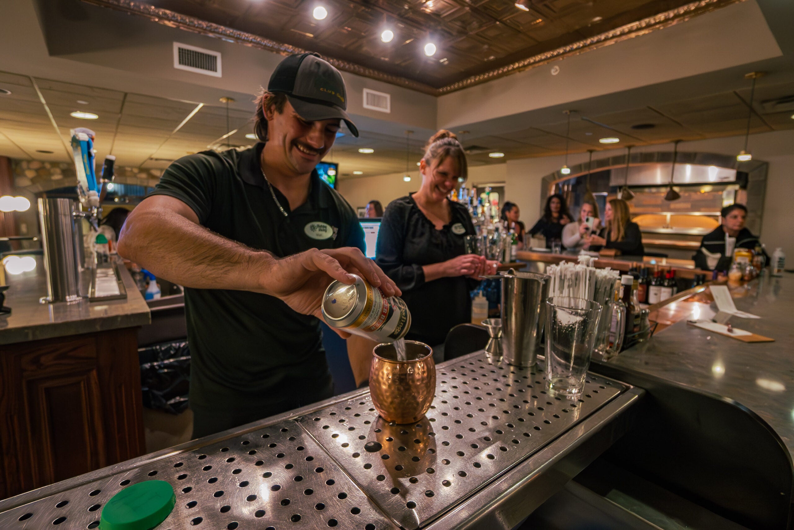 Orang tersenyum sambil membuat koktail bir jahe