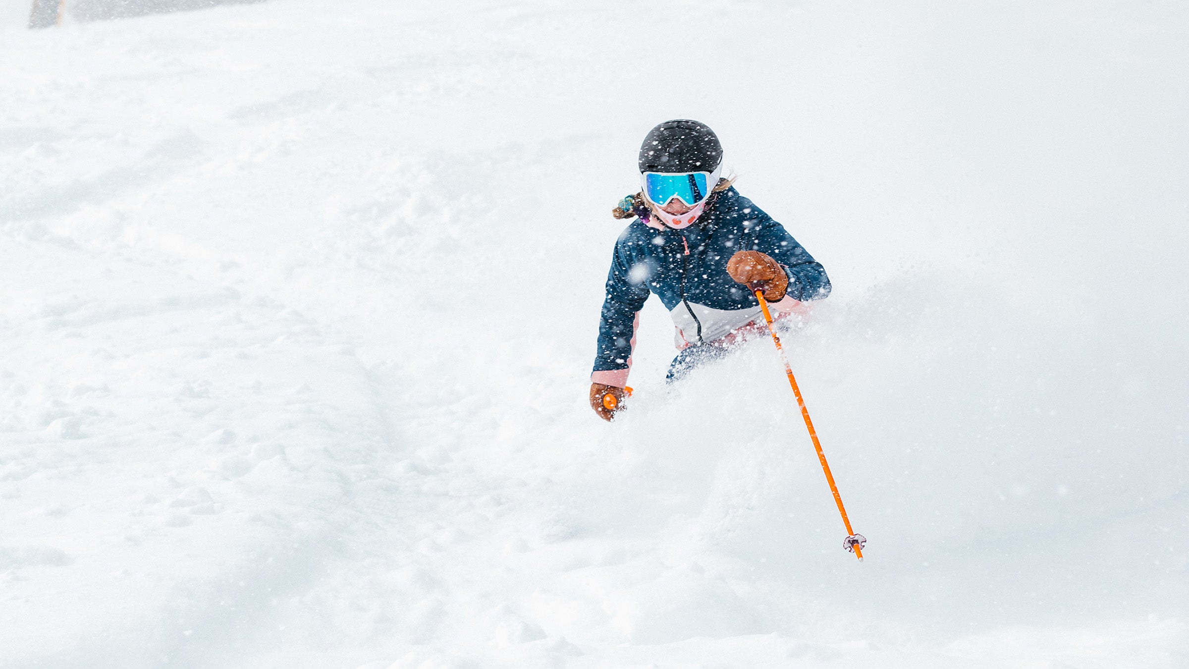 Skier in blue jacket pole planting in powder snow during snowstorm