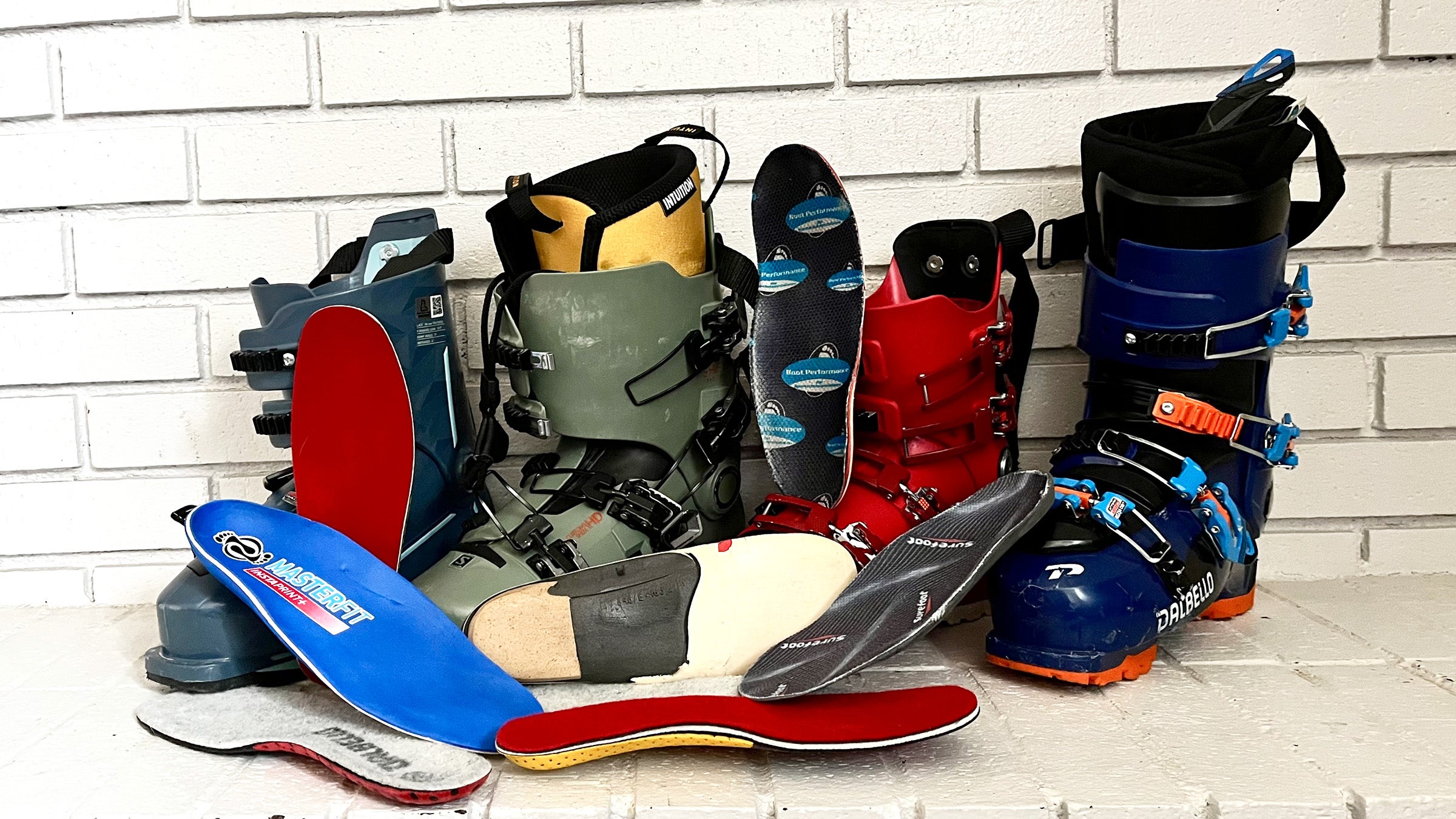 Closeup of ski boots and stock and custom footbeds for ski boots displayed in front of white brick background