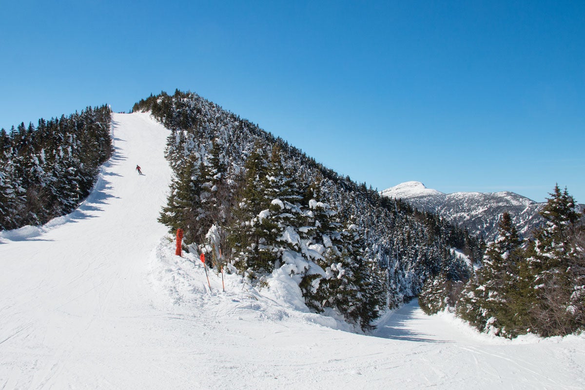 SKI0119-SMUGGS09-byBrianMohrEmberPhoto_S The top of Madonna Mountain is oh-so Vermont, especially with Mt. Mansfield poking up in the distance. This skier is cruising Upper Chilcoot from the…